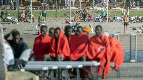 Imagen de archivo de un grupo de migrantes en Tenerife, con varios turistas al fondo.