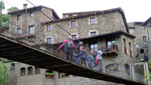 Una família de turistes travessa el pont penjant de Rupit