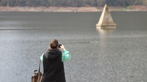 Una dona fotografia el campanar del pantà de Sau Una dona fotografia el campanar del pantà de Sau