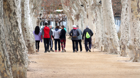 Un grup de persones caminent per la vora de l'estany de Banyoles