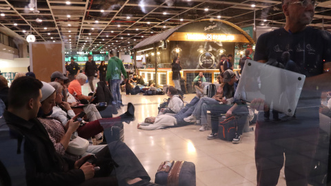 Passatgers amb ordinadors, telèfons mòbils o estirats per descansar a l’estació de Sants de Barcelona, aquest dilluns a la nit després de l'apagada general