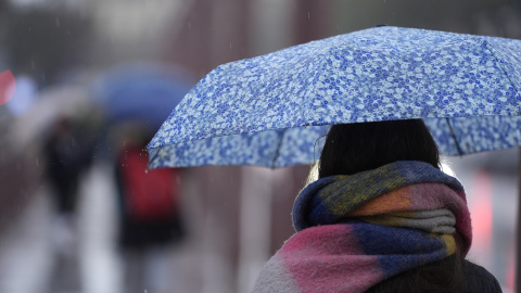 Una persona se protege de la lluvia con un paraguas. Una persona se protege de la lluvia con un paraguas.