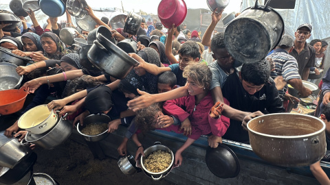Los palestinos luchan por recibir comida caliente distribuida por organizaciones benéficas en medio de los continuos ataques israelíes y el bloqueo total de Gaza.