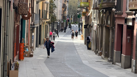 Diverses persones passegen per un carrer del nucli antic d'Olot