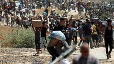 gaza Palestinos caminan con suministros de ayuda que recibieron de la Fundación Humanitaria de Gaza respaldada por Estados Unidos, en Al-Bureij