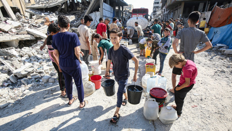 gaza Niños palestinos llevan bidones llenos de agua distribuida por un camión cisterna.