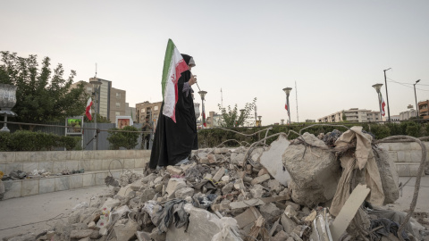 Una estudiante iraní sujeta la bandera de Irán encima de los restos de un edificio destruido en Tehran el 21 de junio de 2025. Una estudiante iraní sujeta la bandera de Irán encima de los restos de un edificio destruido en Tehran el 21 de junio de 2025.