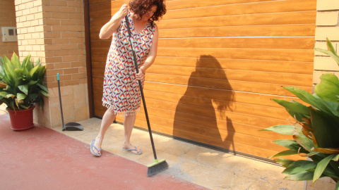 Una veïna d'Aldover escombra les cendres que han arribat fins a la porta de casa seva