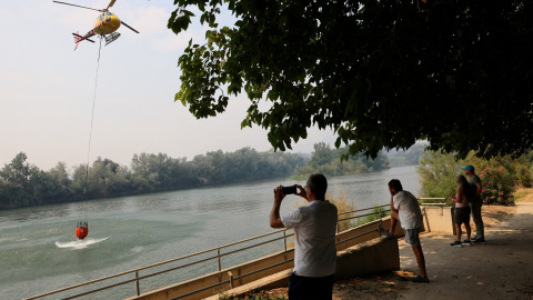La gente observa cómo un helicóptero vuela para ayudar a extinguir un incendio forestal en Tarragona, a 8 de julio de 2025. La gente observa cómo un helicóptero vuela para ayudar a extinguir un incendio forestal en Tarragona, a 8 de julio de 2025.