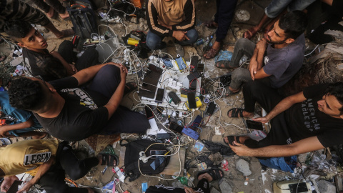 Palestinos cargan sus teléfonos móviles y baterías en una estación de carga junto a la Sociedad de la Media Luna Roja Palestina.