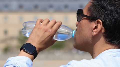 Un hombre bebe agua durante la ola de calor en Madrid.