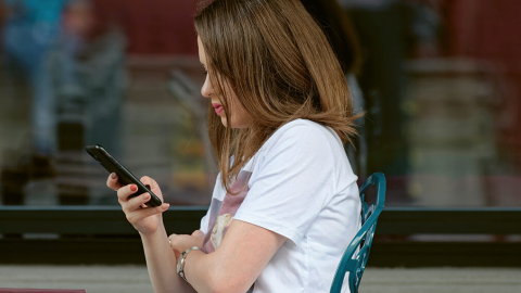 Una estudiante, en clase con un móvil.
