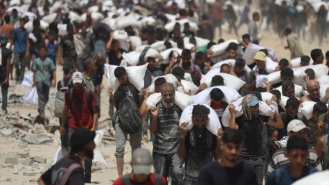 Ciudadanos palestinos transportan sacos de harina, este domingo.