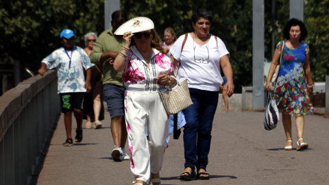 Una dona es protegeix amb un ventall mentre camina per la passarel·la del Liceu Escolar a Lleida