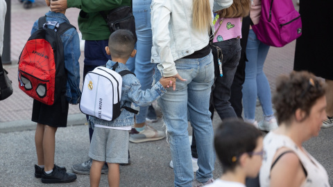Varios niños esperan para entrar al colegio el primer día de curso escolar