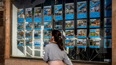 Una mujer pasa junto a una inmobiliaria en Santander.
