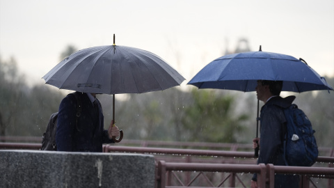 Varias se protegen de la lluvia con un paraguas. Varias se protegen de la lluvia con un paraguas.