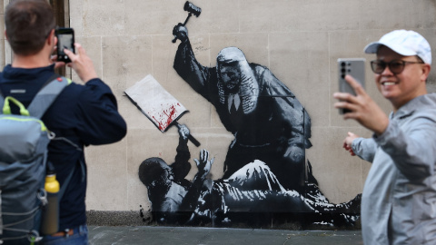 Varias personas hacen fotos y selfis ante el último mural de Banksy, antes de que fuera borrado de la fachada del Tribunal Superior de Londres.