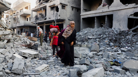 Varios palestinos buscan entre los escombros de un edificio tras un ataque israelí.