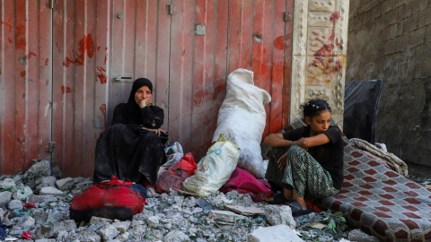 Dos mujeres palestinas con sus enseres después de que su casa fuera alcanzada por un ataque aéreo israelí, en el campo de refugiados de al-Shati (Playa), en Ciudad de Gaza.