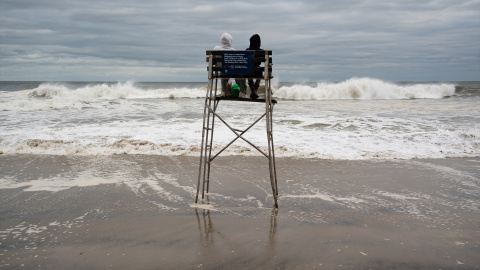 imagen-huracan-Erin-playa-Queens Dos personas sentadas en la silla del socorrista en una playa de Queens