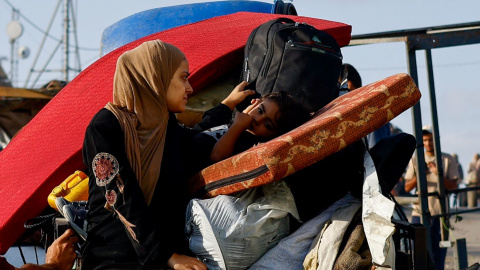 Una mujer palestina desplazada y un niño, que huyen del norte de Gaza debido a una operación militar israelí, sentados en un vehículo repleto de pertenencias, este 23 de septiembre de 2025.