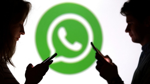 Unos jóvenes con sus smartphones en frente del logo de la aplicación Whatsapp. Unos jóvenes con sus smartphones en frente del logo de la aplicación Whatsapp.