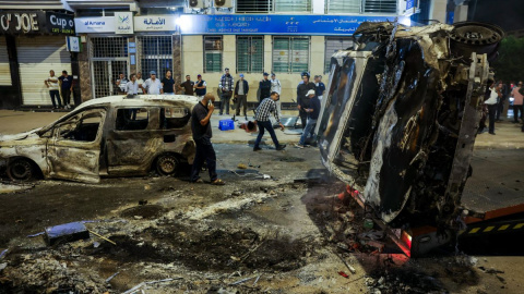 AFP__20251002__77FD3XK__v1__HighRes__MoroccoPoliticsHealthEducationProtest Personas observan vehículos incendiados durante una manifestación liderada por jóvenes.