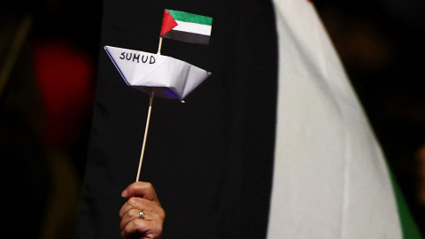 Un manifestante sostiene un barco de papel en apoyo a la Flotilla.