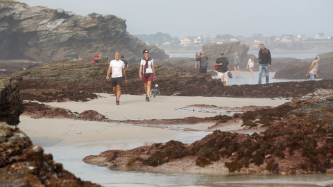 Varias personas pasean por la playa de As Catedrais, en Ribadeo (Lugo), en una foto de archivo.
