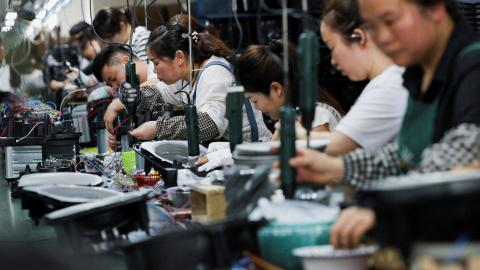 Trabajadoras y trabajadores en una línea de montaje de 'airfryers' de una empresa de electrónica en la localidad de Ningbo, en la provincia china de Zhejiang.