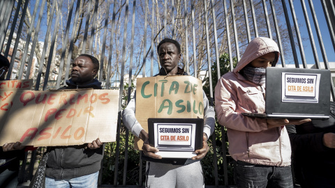 Varios solicitantes de protección internacional sujetan pancartas durante una concentración.