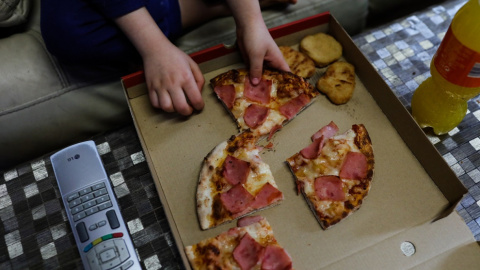 Foto de archivo de un niño cenando pizza.