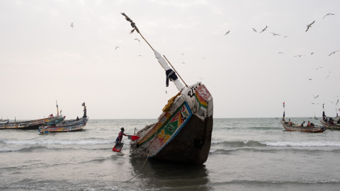 Un hombre carga cajas en una piragua pesquera en Serrekunda, Gambia (Marzo de 2025)