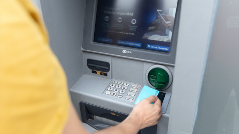 Un hombre saca dinero de un cajero automático.