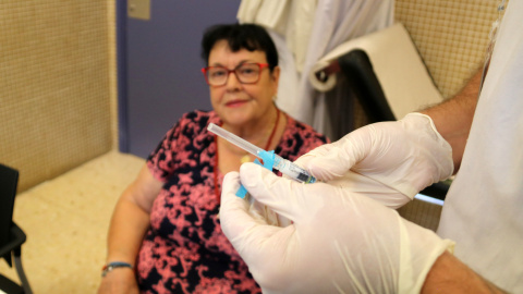 Una pacient mira la vacuna de la grip que li preparen en una consulta del CAP Baix Ebre de Tortosa