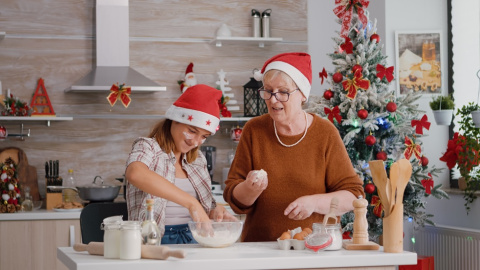 Una mujer mayor con una niña cocinando en vísperas de las fiestas de Navidad. Una mujer mayor con una niña cocinando en vísperas de las fiestas de Navidad.