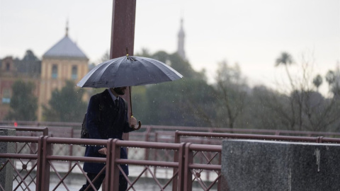Foto de archivo de una persona que se protege de la lluvia con un paraguas en Sevilla. Foto de archivo de una persona que se protege de la lluvia con un paraguas en Sevilla.