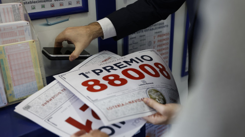 El propietario de la administración sujeta el cartel del primer premio.