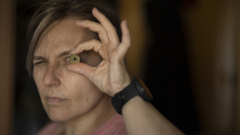 mujer_mirando Una mujer mira a través de una moneda de las antiguas pesetas, en una imagen de archivo.