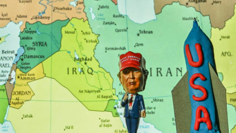 Una estatua en miniatura del presidente estadounidense Donald Trump junto a una maqueta de una bomba antibúnker, con un mapa de Oriente Medio e Irán como telón de fondo, expuesta en Kananaskis,(Canada) 19/06/25