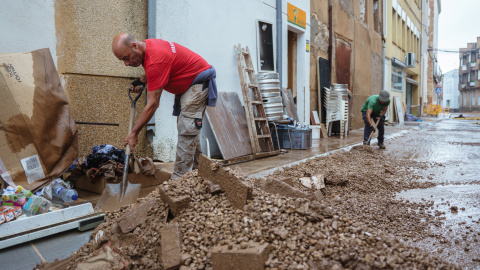 Dues persones netegen baixos i un carrer afectats pel temporal de pluges a Santa Bàrbara