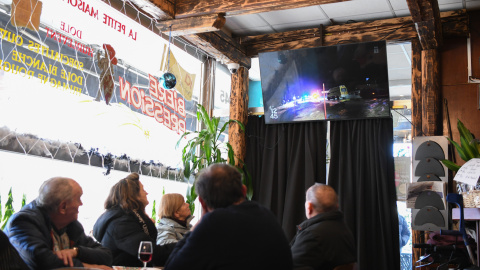 Varias personas ven por televisión en un bar de Ginebra las noticias sobre el incendio de Crans Montana.