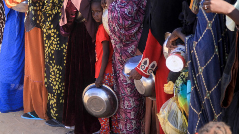 Una niña sudanesa que huyó de El-Fasher hace fila junto a otras mujeres para recibir una comida gratuita en el campamento de Al-Afad para personas desplazadas, al norte de Sudán (20.11.2025)