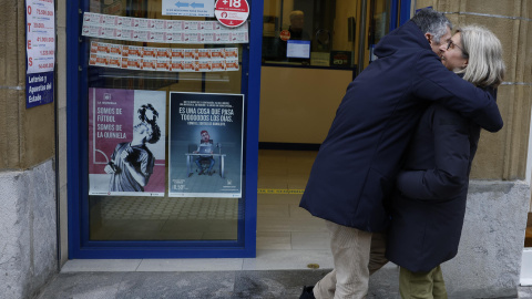 lotería Pedro Arroyo, propietario de la administración número 22 de Donostia, celebra con una clienta tras vender diez décimos del número 06703, primer premio del sorteo extraordinario de la lotería del Niño