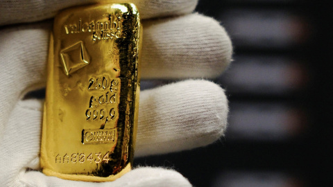Un empleado sostiene un pequeño lingote de oro en una tienda en Barcelona. Un empleado sostiene un pequeño lingote de oro en una tienda en Barcelona.