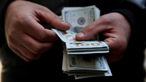Un empleado de un a casa de divisas con un fajo de billetes de dólar, en Teherán.