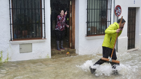 Vecinos de Grazalema (Cádiz) intentan achicar agua de sus casa y locales inundados por las intensas lluvias.