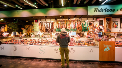 Un hombre frente a un puesto de carne y embutidos en el mercado de San Antón (Madrid). Un hombre frente a un puesto de carne y embutidos en el mercado de San Antón (Madrid).