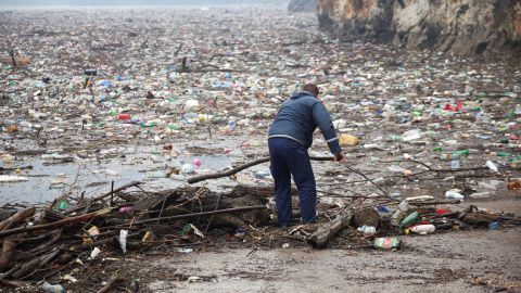 Un trabajador limpia la basura de un vertedero flotante en el río Drina, en Bosnia Herzegovina.